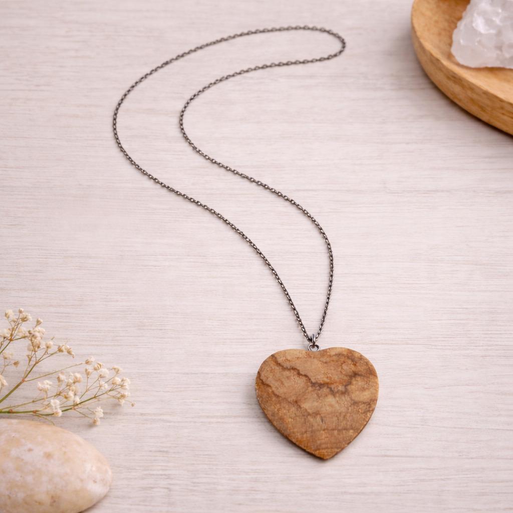 Collier avec pendentif cœur en Palo Santo, posé sur un fond clair dans une ambiance naturelle